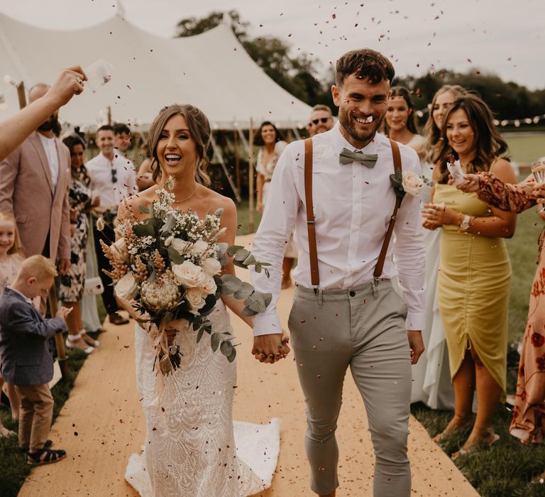 Bride & groom walk through confetti as guests throw confetti around them | Mark Bamforth Photography