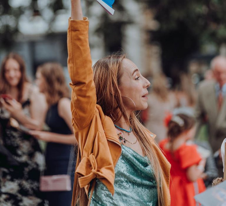 Wedding guest holds up fan complete with Pride colours  | Kim Williams Weddings