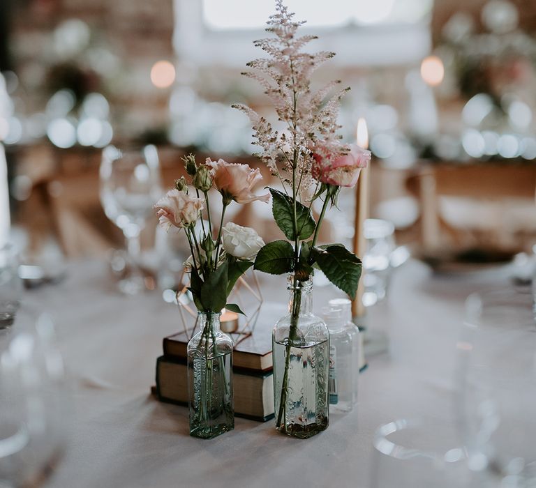 Rose and astilbe flower stems in bottles as wedding centrepiece decor 