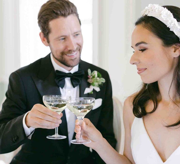 Bride in an applique headband toasting champagne glasses with her groom in a Tuxedo at Botley's Mansion 