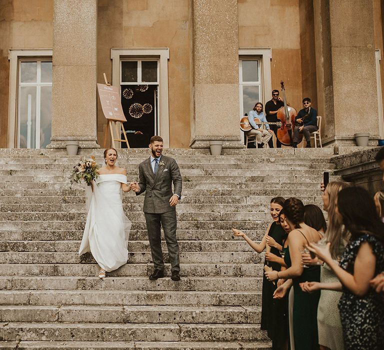 Bride & groom walk down grand steps after wedding ceremony at The Grange Hampshire