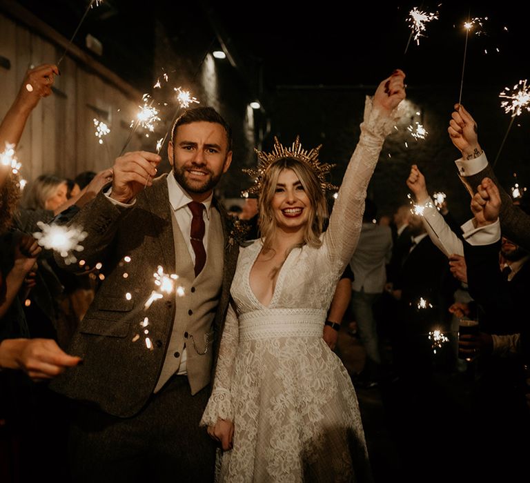 Sparkler moment with bride in a lace wedding dress and gold crown and groom in a tweed suit at Lyde Court 