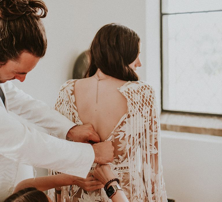 Wedding guests do up brides dress on the morning of wedding day