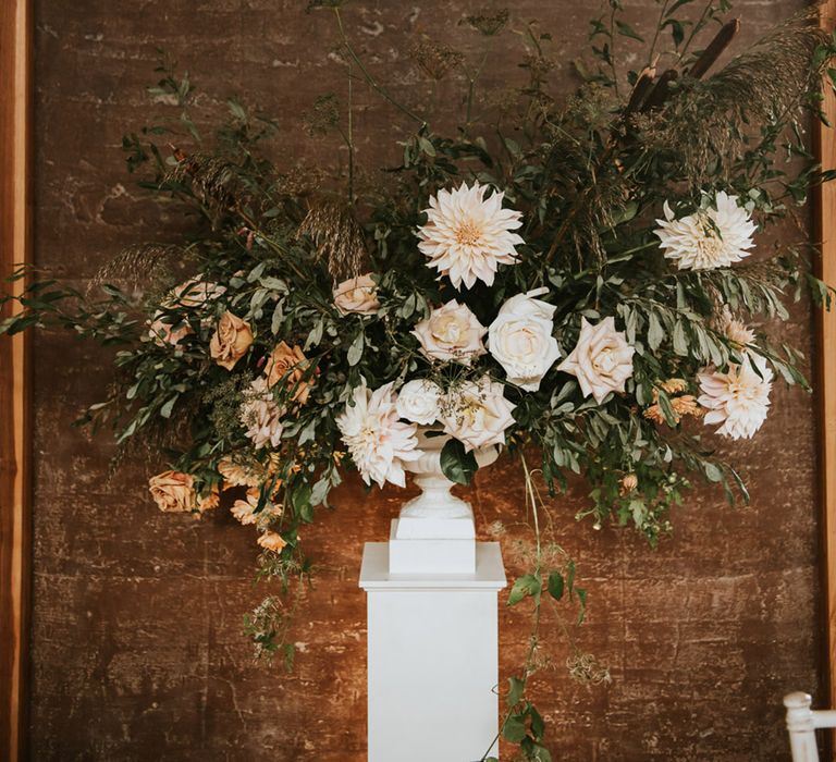 Roses, dahlias and foliage wedding flower arrangement on a plinth