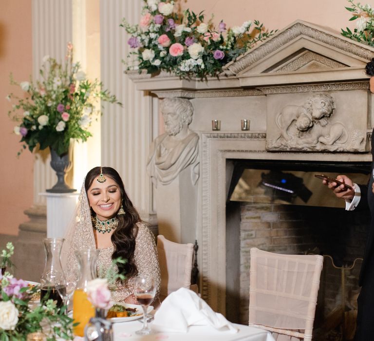 Bride & groom smile at one another as groom reads wedding speech during reception