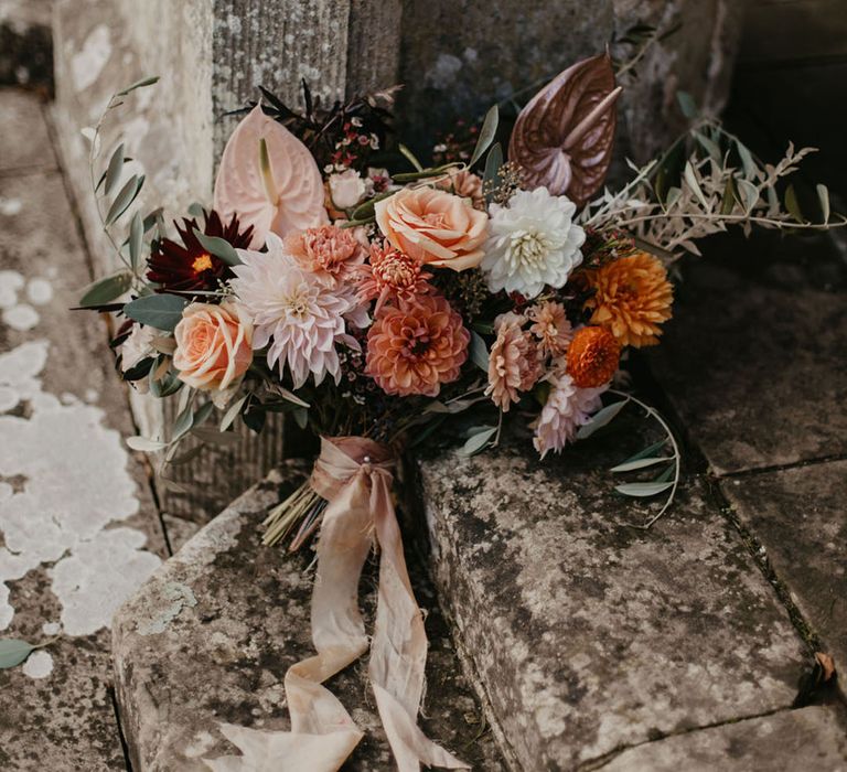 Dahlia wedding bouquet with anthuriums, roses and foliage tied with ribbon