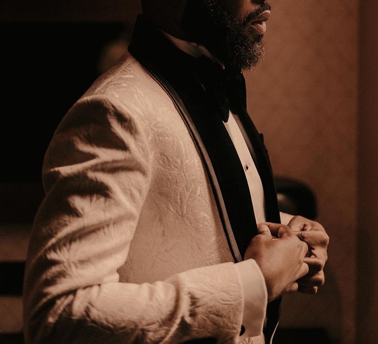 Black groom in white brocade tuxedo jacket 