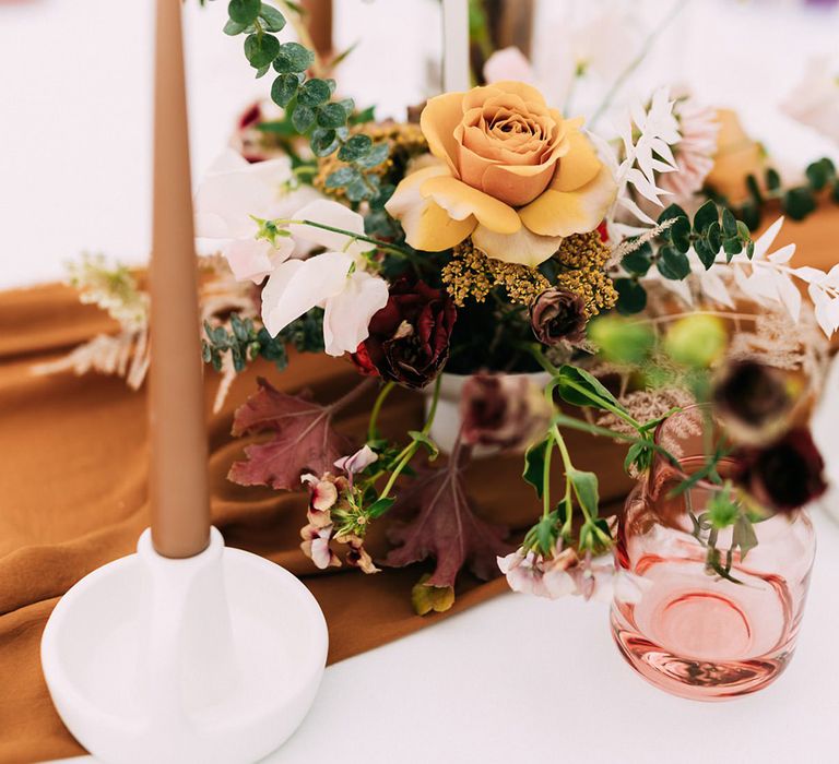 Autumnal yellow rose flower centrepiece and table numbers on dining tables