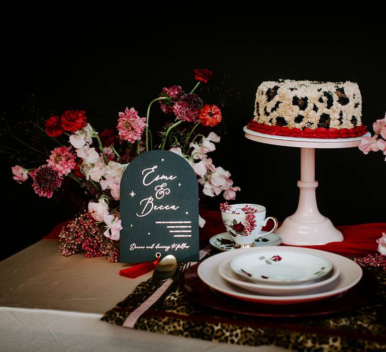 Place setting with gold table cloth, leopard print place matt, black and gold wedding stationery and leopard print buttercream wedding cake 