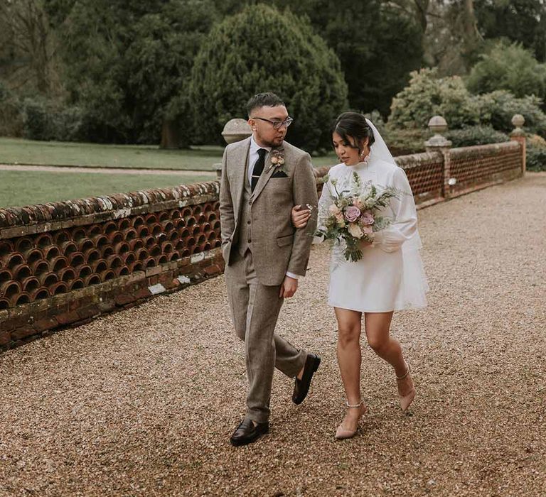 Bride in Vanessa Cocchiaro wedding dress and neutral bouquet, groom in Tru Clothing suit with a neutral boutonniere