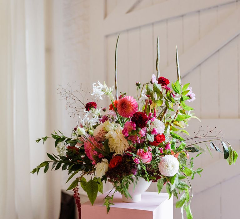 Pink and red wedding flowers in white vase on pedestal for colourful party wedding in London city