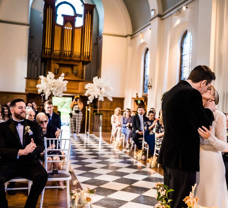 Bride and groom have their first kiss as a married couple as wedding guests clap