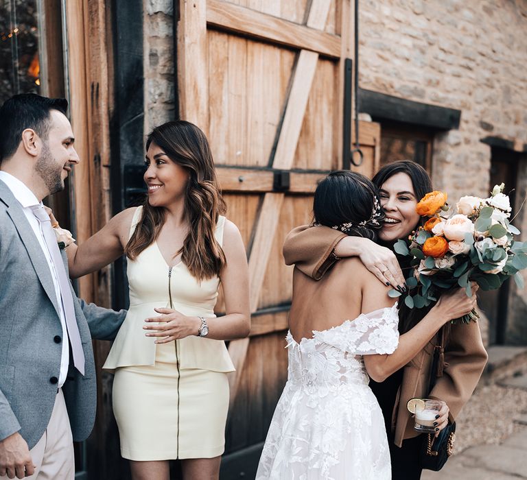 Bride and groom hug their wedding guests who offer them congratulations