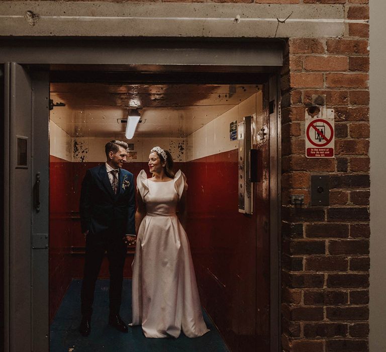 Bride and groom stand in lift at their industrial wedding venue, Bowers Mill