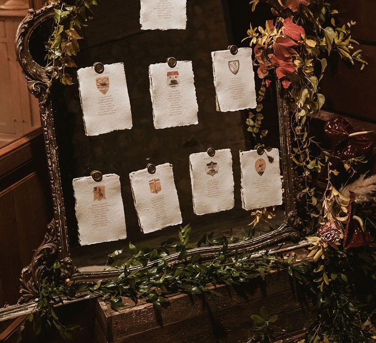 Table plan on vintage styled board complete with white stationery and surrounded by foliage 