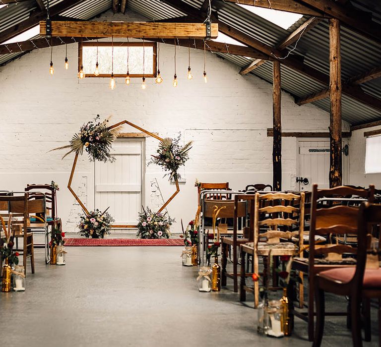 Festoon lights, dried flowers and candle lanterns line the aisles for industrial wedding 