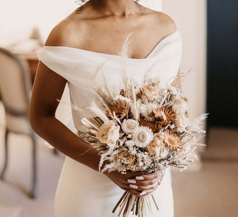 Black bride in off the shoulder wedding dress carrying a dried flower wedding bouquet with pampas grass 