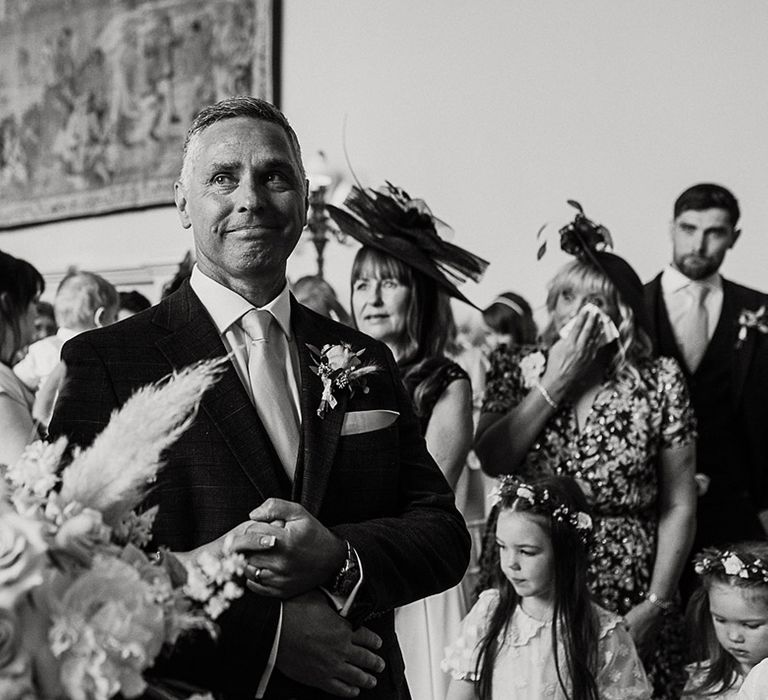 Father of the bride smiles at the groom as he walks her down the aisle 