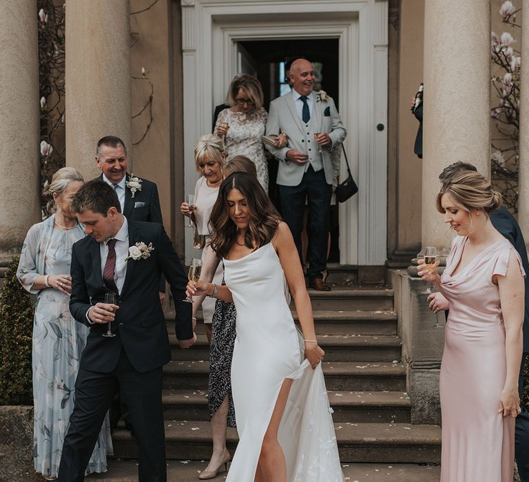 Wedding guests and the bride and groom leave the ceremony with a glass of champagne to celebrate 