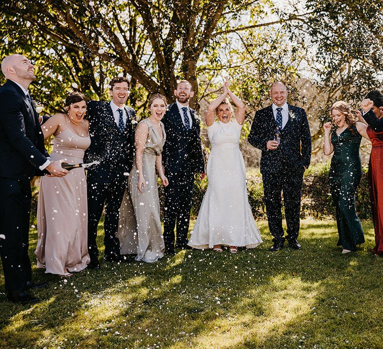 Bridesmaid waves and pops some champagne over the wedding party 