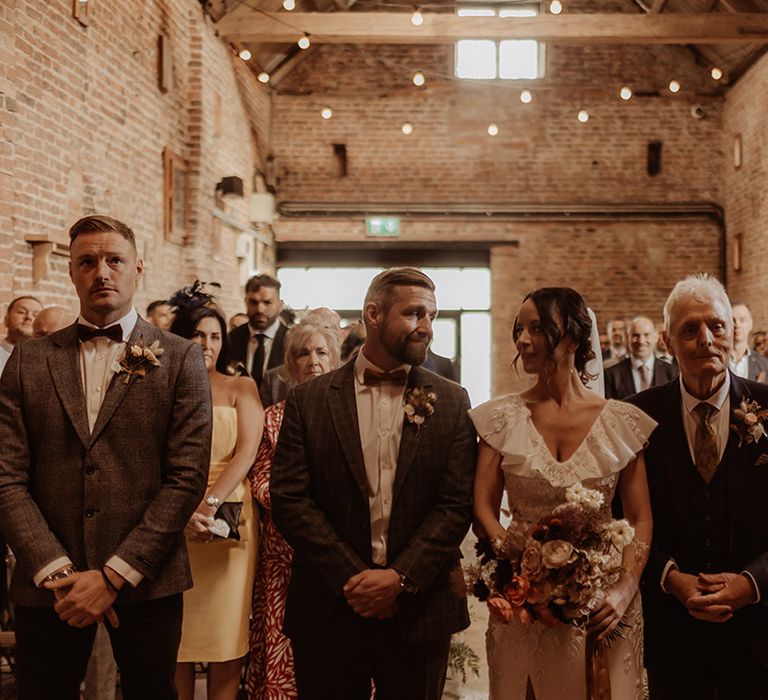 Groom and best man standing with the bride and her father at the altar for the wedding ceremony 