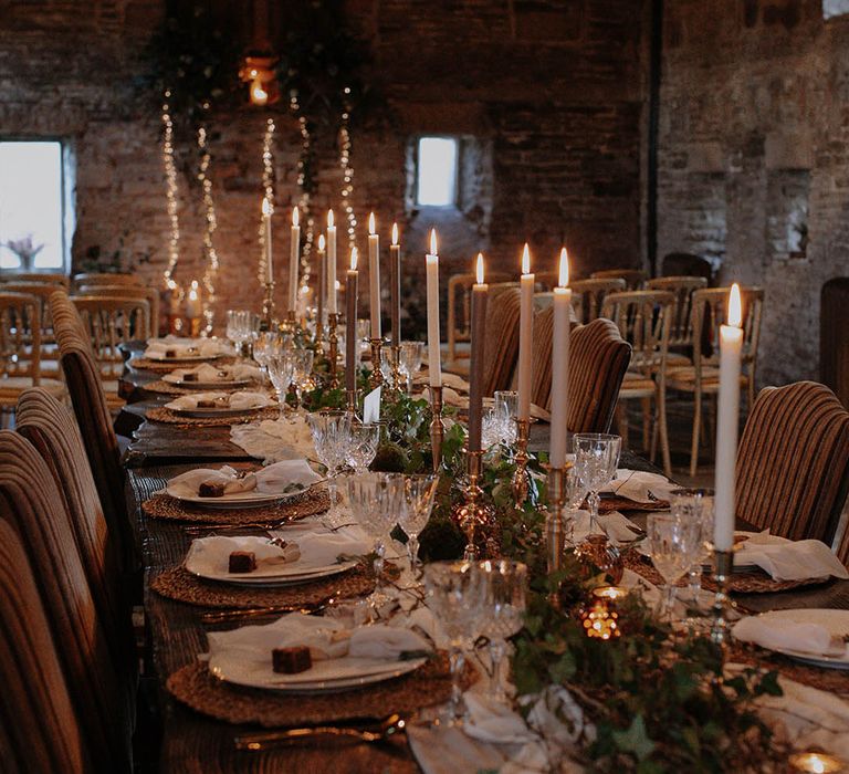 Gold candleholders and detailing over a rustic winter tablescape with mini brownie favours, soft candlelight and real foliage 