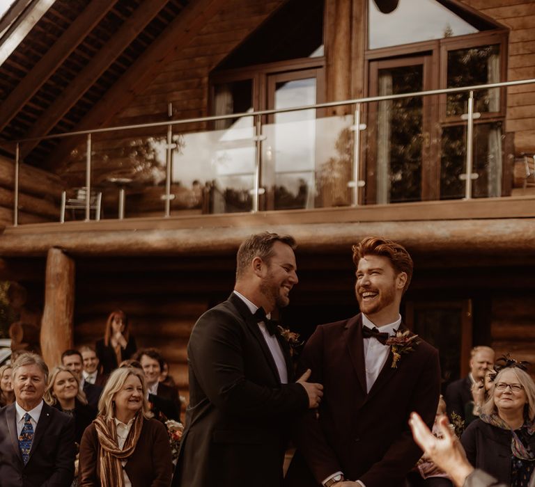 Grooms share an intimate sweet moment for their wedding ceremony as the guests watch their wedding 