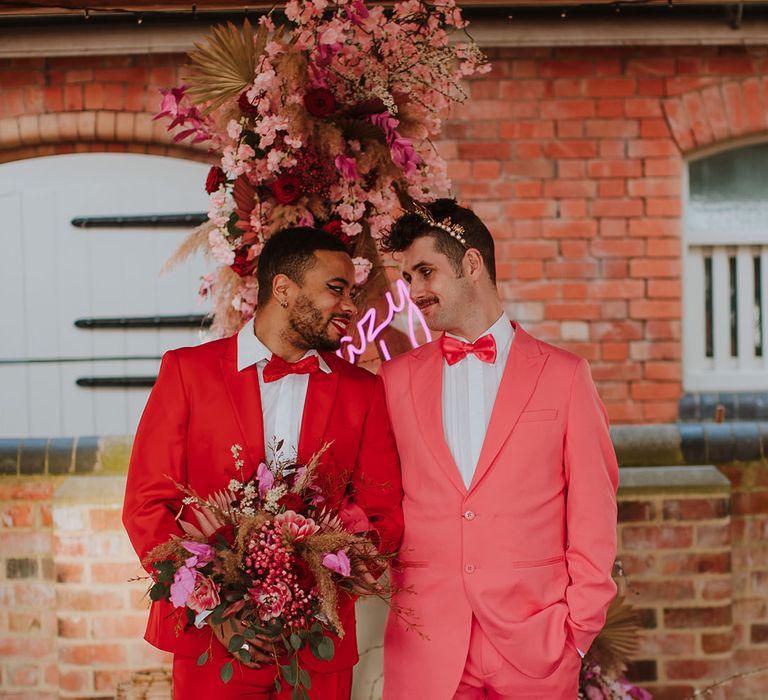 Groom's wearing the Pantone Color of the Year 2023 with magenta pink and red suits with bright flowers 