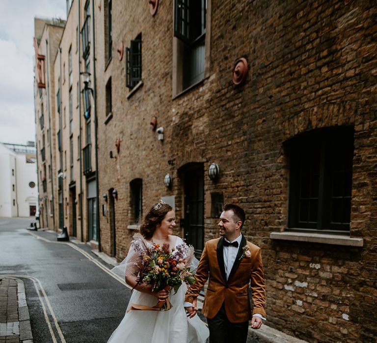 Bride and Groom hold hands and walk through the streets at London Wedding