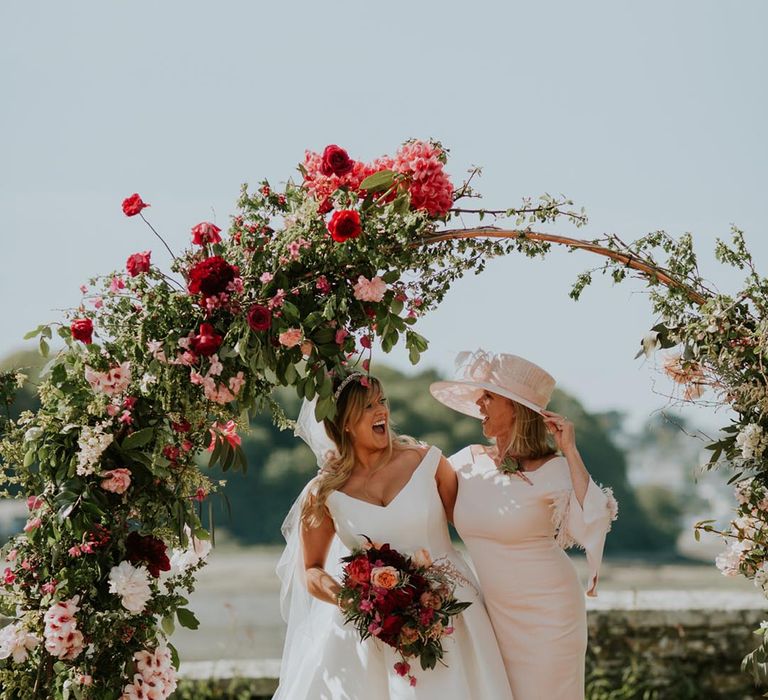 Wedding moongate altar decoration with pink and red flowers with the bride smiling with a wedding guest 