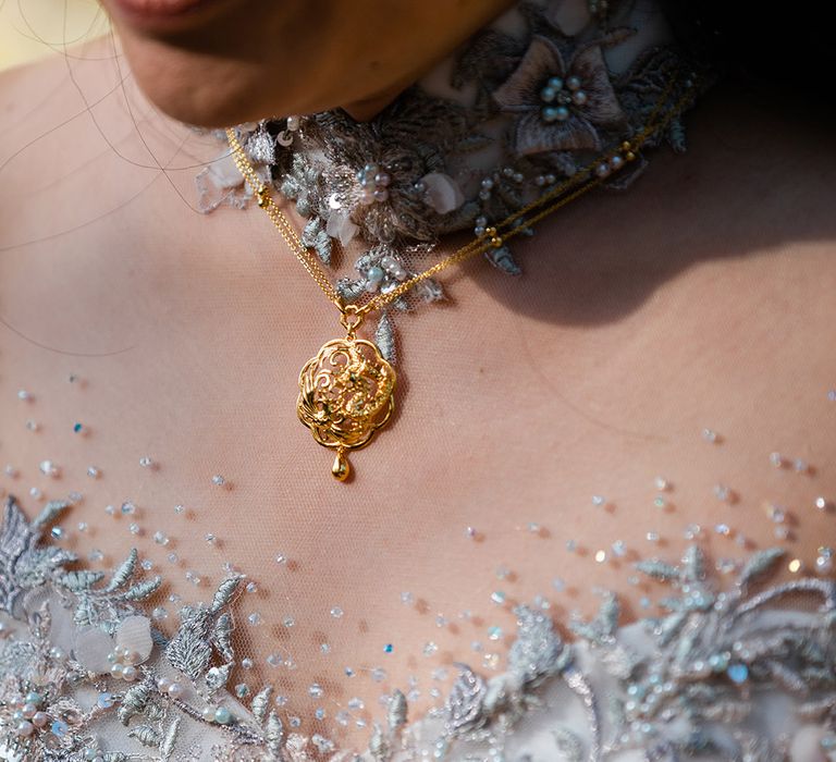 Bride wears gold necklace and beautifully embellished reception dress made bespoke 