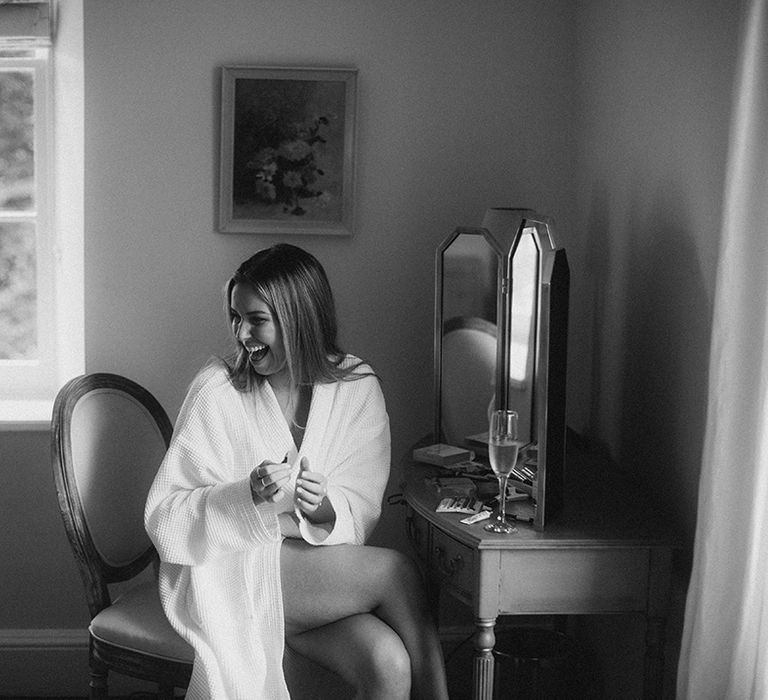 Bride wears white dressing gown whilst getting ready on the morning of her wedding day