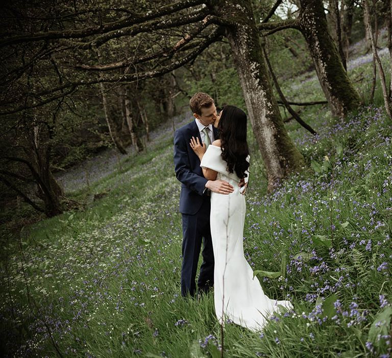 The bride and groom share a kiss in pretty woodland area surrounding the Hidden River Cabins wedding venue for their couple portraits