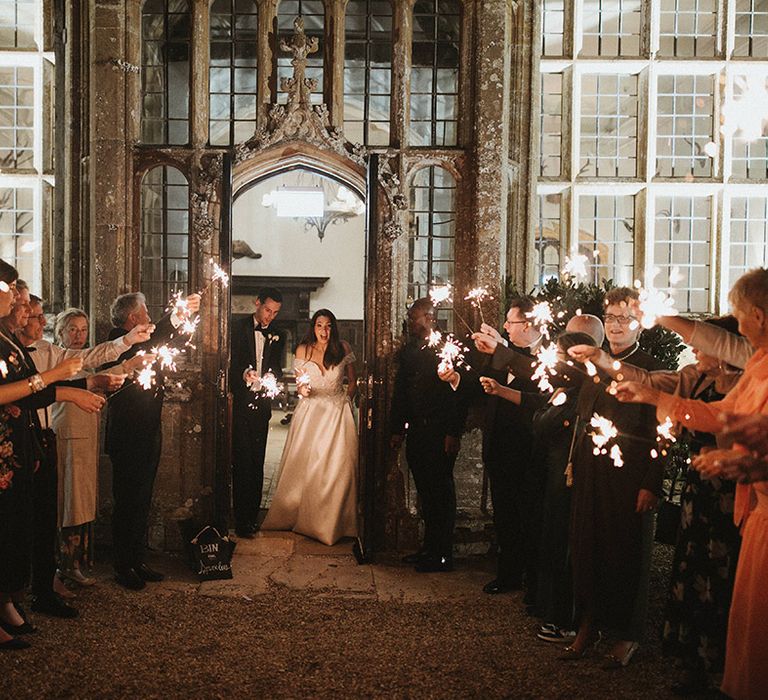 Wedding guests wave sparklers as the bride and groom exit from their reception 