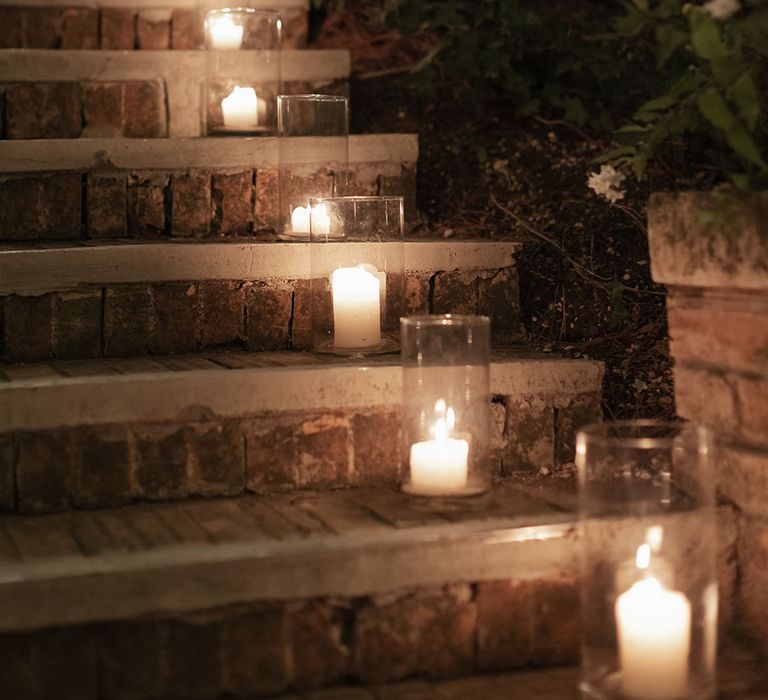 White pillar candles in glass vases line stairway 