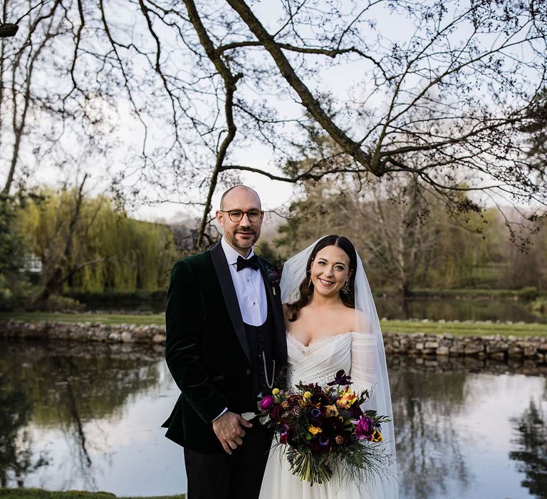 Groom in green velvet tuxedo with the bride in an off the shoulder long sleeve wedding dress smiling for a cute couple portrait