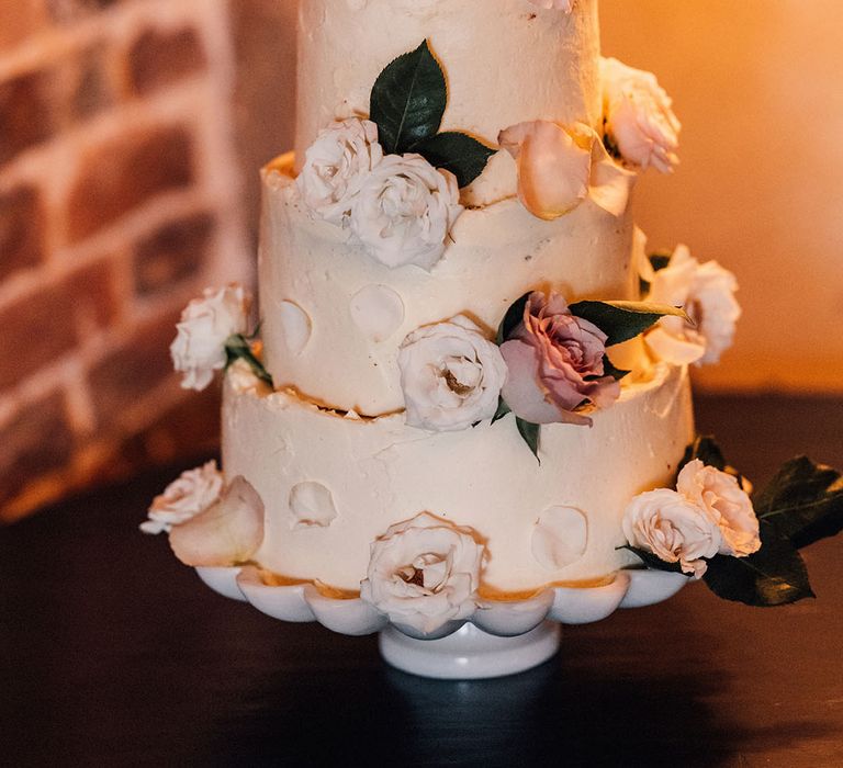 Three tier buttercream wedding cake with pink and white garden rose decorations 