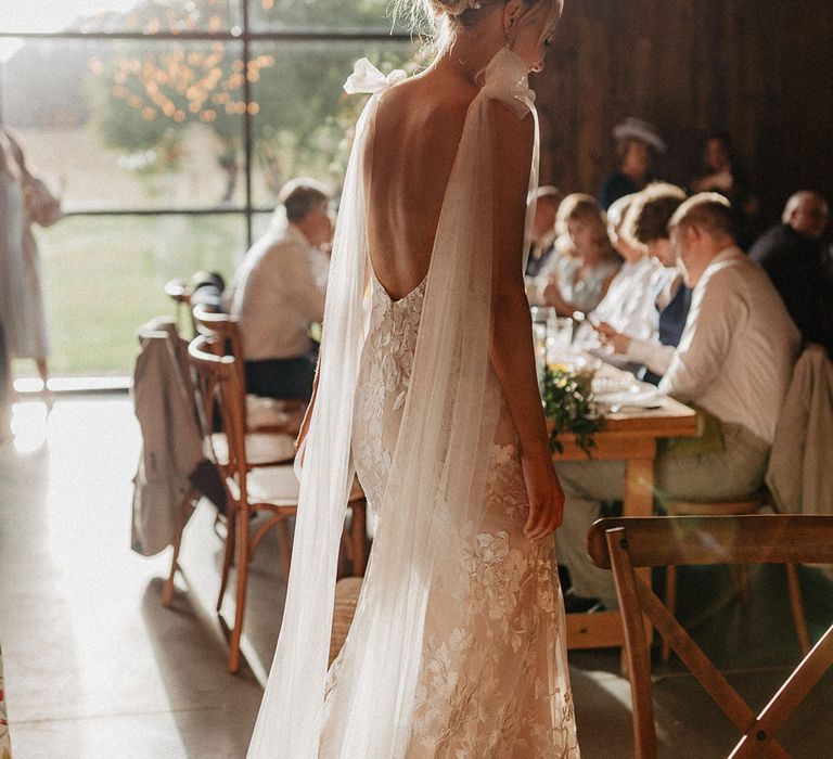 The bride in a low back Made With Love wedding dress with her blonde hair worn in an updo decorated with pearl hair pins 