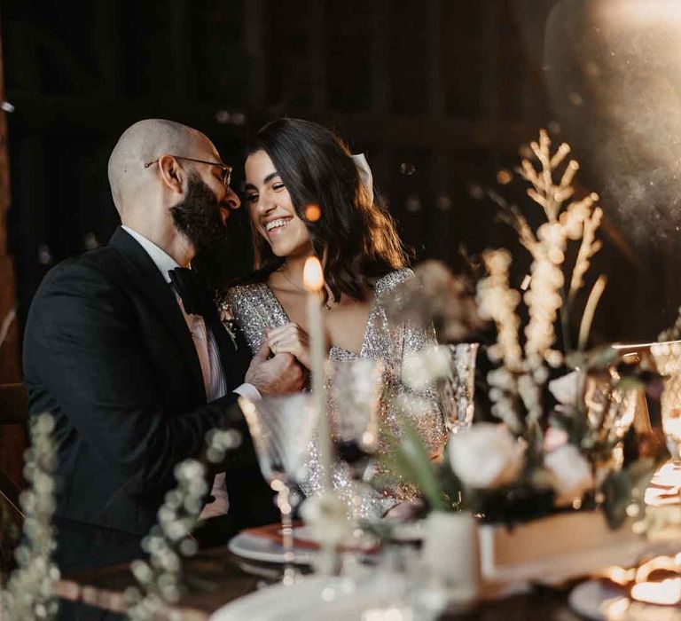 Bride and groom laughing together sat at rustic luxe wedding tablescape at Elmley Nature Reserve wedding venue 