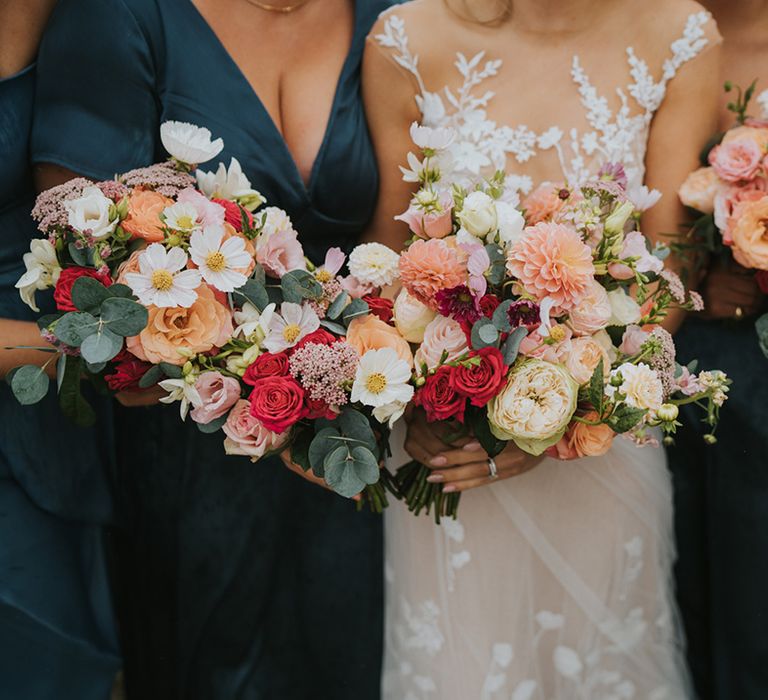 Pastel wedding bouquets from the bride and bridesmaid with pink roses, dahlias, and white cosmos 