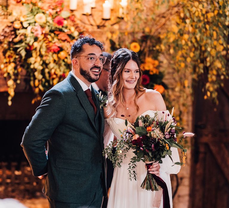 Bride in off the shoulder wedding dress with the groom at their autumnal rustic wedding 