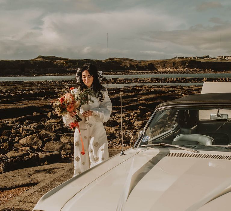 Bride in sparkly Bowen Dryden jumpsuit with chunky belt and large white hair bow accessory 