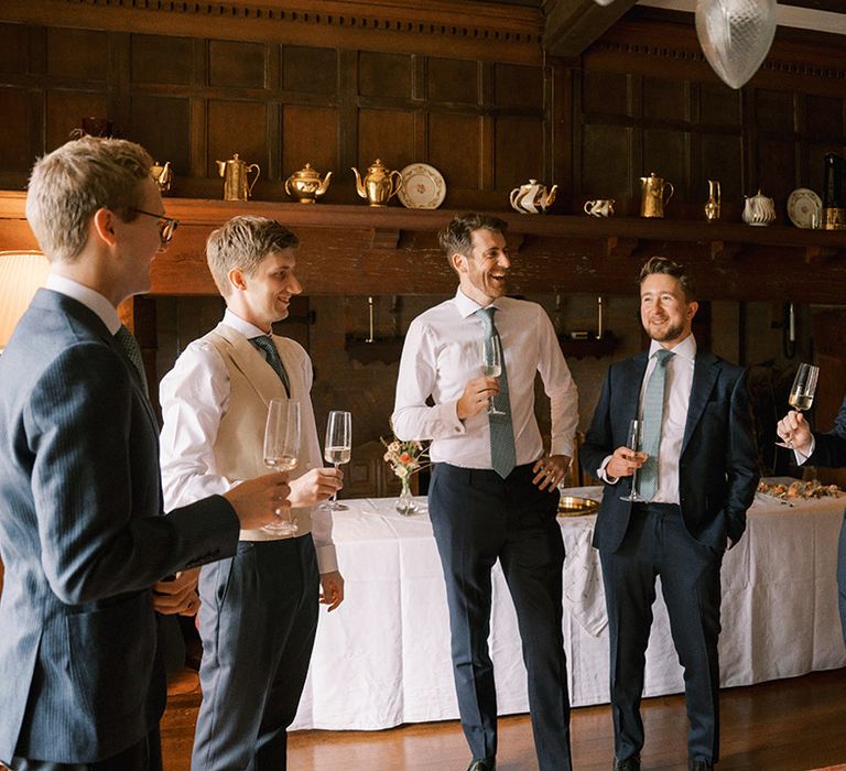 Groom and groomsmen in navy suits with white shirts and green ties 