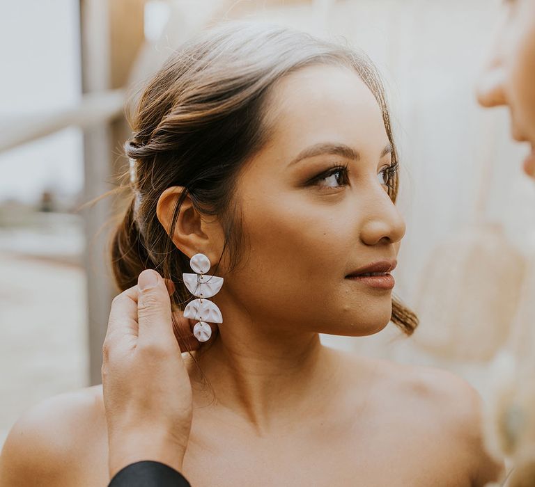 bride with pinned wedding hairstyle and geometric earrings 