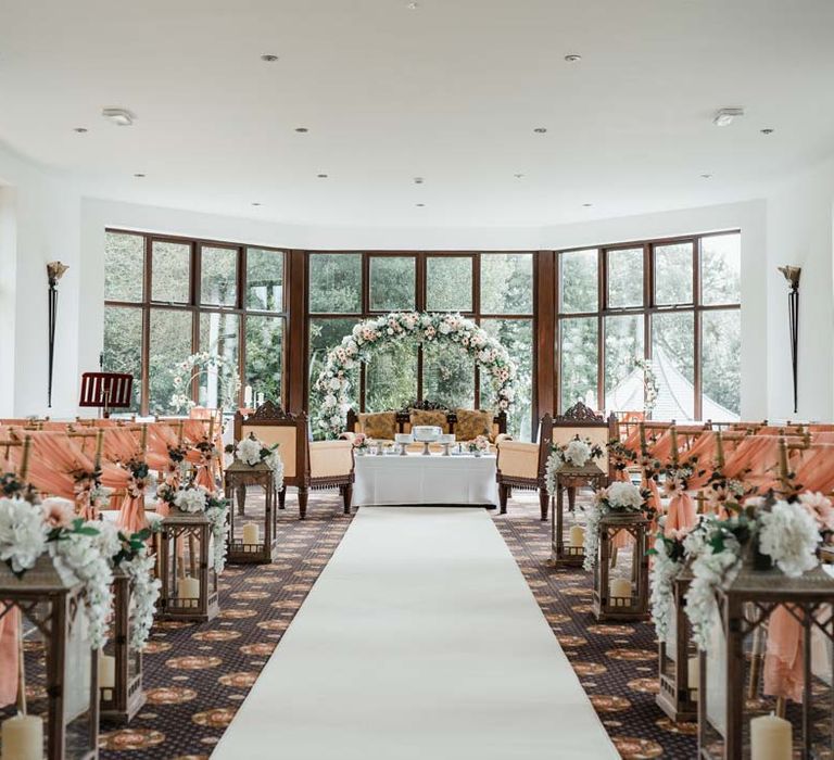 Bron Eifion reception room with floral arch, baby pink chair back decor with white flowers and foliage for Burmese wedding 