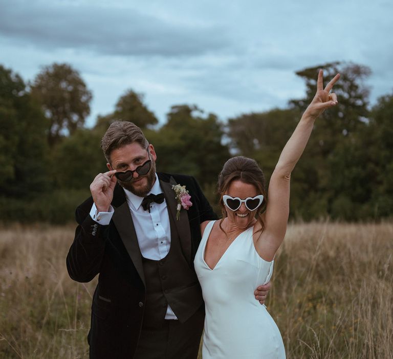 Bride in satin slip wedding dress by Made With Love with sunglasses posing with the groom for fun wedding photo