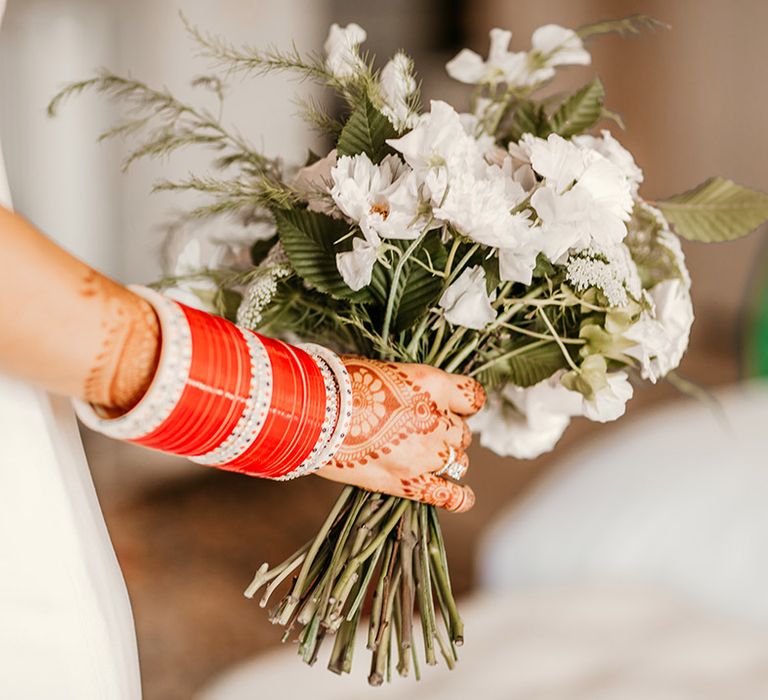 Bride wearing red bangle jewellery and white wedding bouquet 