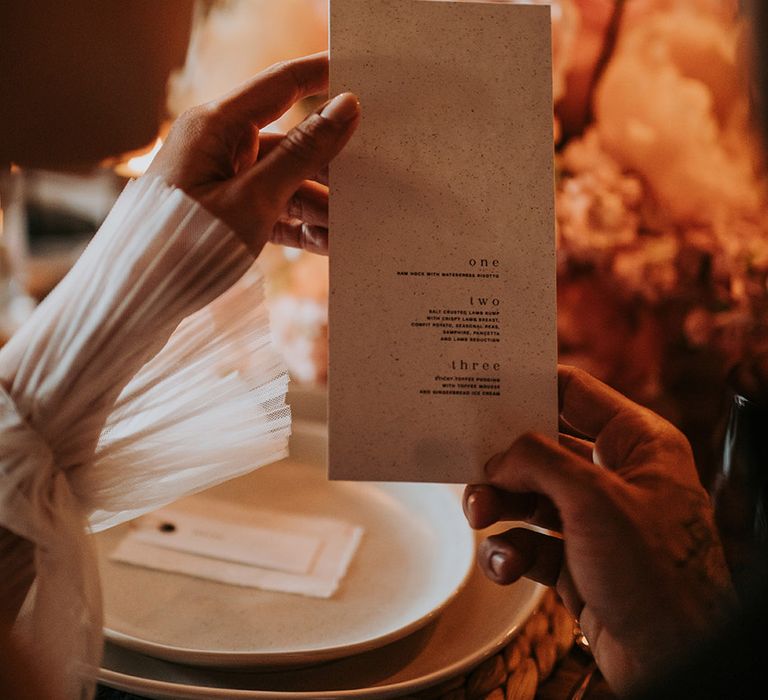 Bride holding up wedding menu at rustic barn wedding 