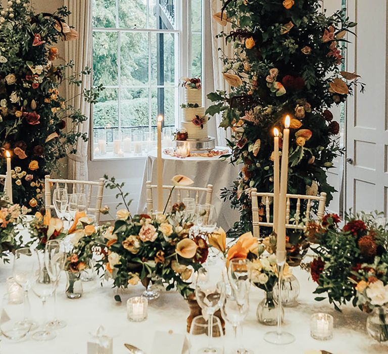 Wedding flower columns behind the wedding table with orange roses and lilies 