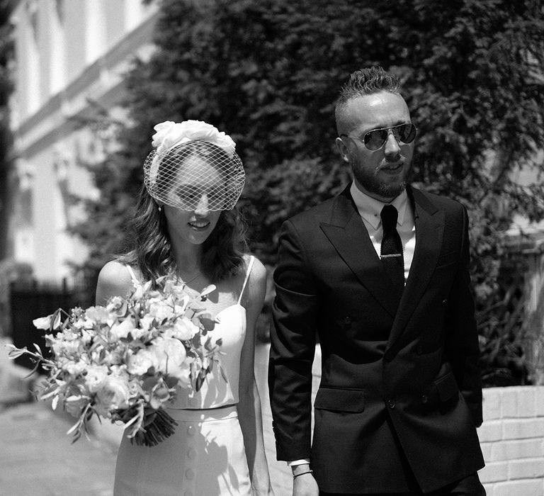 stylish couple at London city wedding in a black suit and bridal separates with headband and blush veil 